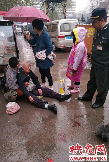 女孩為倒地老人撐傘。