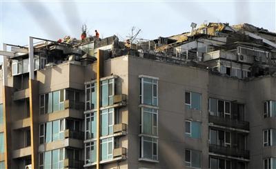 　　昨日，身穿橘黃色馬甲的工作人員在人濟(jì)山莊樓頂拆除違章建筑。新京報(bào)記者 吳江 攝