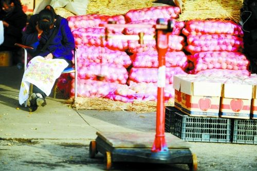 水果批發(fā)市場(chǎng)內(nèi)，沒有客戶時(shí)，商戶在繡十字繡