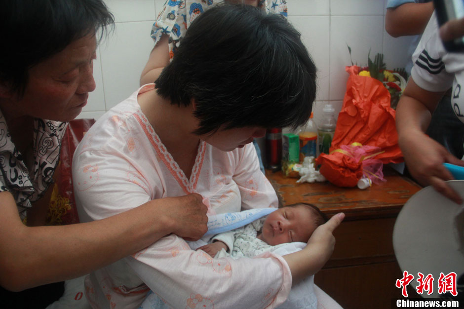 圖為久別重逢，獲救嬰兒母親悉心撫摸愛子。張一辰 攝