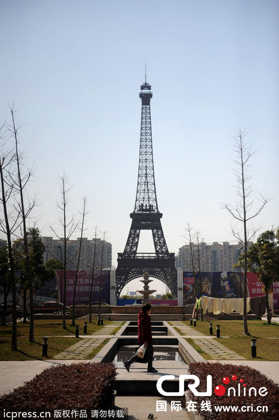 　2014年3月21日，杭州天都城，農(nóng)民在山寨埃菲爾鐵塔下耕作。圖片來源：東方IC