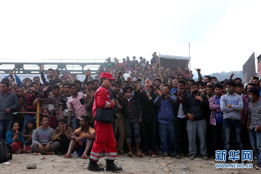 圍觀的尼泊爾民眾在中國國際救援隊成功搜救出幸存者后向搜救隊員歡呼致意。