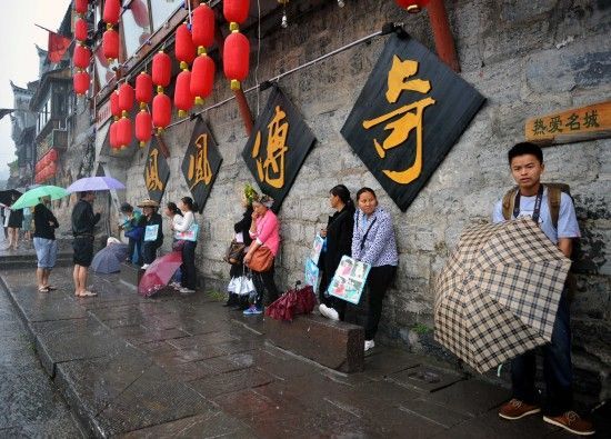 　4月29日上午11時20分，一些游客和古城當(dāng)?shù)氐木用穸阍谝粋€酒吧的屋檐下避雨。這些當(dāng)?shù)鼐用褚詾橛慰团恼罩\生，一場降雨讓他們的生意更加清淡。