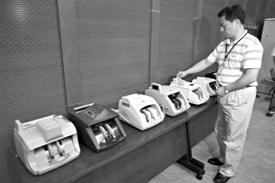 昨日，央行工作人員用各種驗鈔機對C1F9假幣進行測試，機器均能及時作出異常報警反應(yīng)。新京報記者 浦