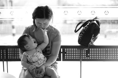 昨日，肯德基京廣中心店門口，姜女士提起跟養(yǎng)父母的關(guān)系時(shí)落淚，懷中9個(gè)月的女兒笑著跟她玩。新京報(bào)記者 薛珺 攝