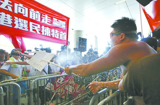17日，在香港立法會(huì)外，一名反對(duì)政改的男子向支持派人群投擲標(biāo)牌。