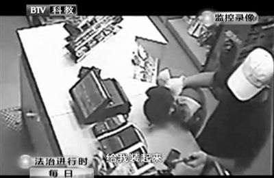 戴帽男子一手掐住加油站營業(yè)員，一手持發(fā)令槍指向另一營業(yè)員，要求“把錢給我裝起來”。