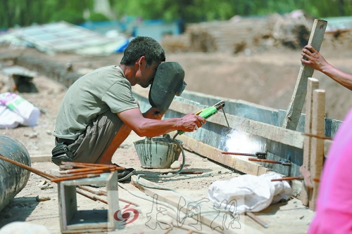 　正午陽光下，工地上的焊接工人還在認(rèn)真工作。