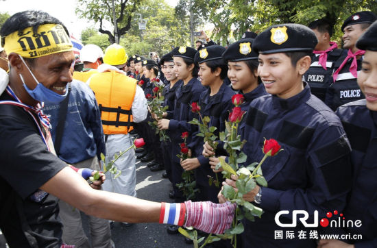2013年12月03日,曼谷總理府與曼谷警署允許反政府示威民眾進(jìn)入,雙方進(jìn)入暫時(shí)“停戰(zhàn)”狀態(tài)迎接泰王生日。曼谷警察總署,女警們手持鮮花送給反政府示威民眾。圖片來(lái)源:Manish Swarup/東方IC