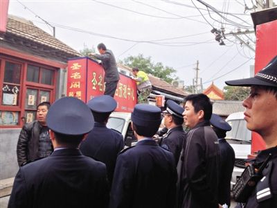 昨日下午,東城區(qū)工商、城管、公安等部門,對(duì)雍和宮附近的預(yù)測(cè)中心進(jìn)行清理整頓,站在車頂?shù)膬擅と苏鸪患摇邦A(yù)測(cè)中心”的招牌。因雍和宮、白云觀等文化景點(diǎn)外聚集大量算命先生,被媒體稱為“算命一條街”。本版攝影/新京報(bào)記者 李寧 攝