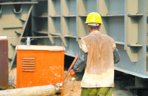 工地上，一建筑工人的衣服被汗水浸透。