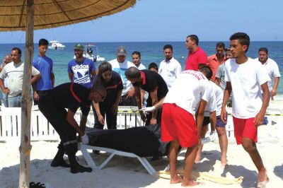 6月26日，在突尼斯蘇塞，救生員和醫(yī)務人員在發(fā)生襲擊事件的海灘運送一名死者的遺體。新華社發(fā)