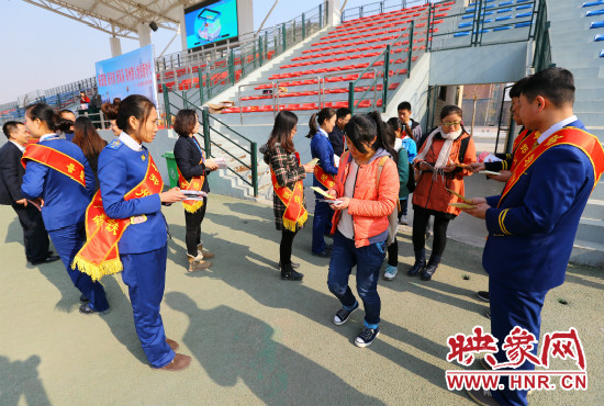 活動現(xiàn)場工作人員給同學們發(fā)放宣傳冊、環(huán)保袋。