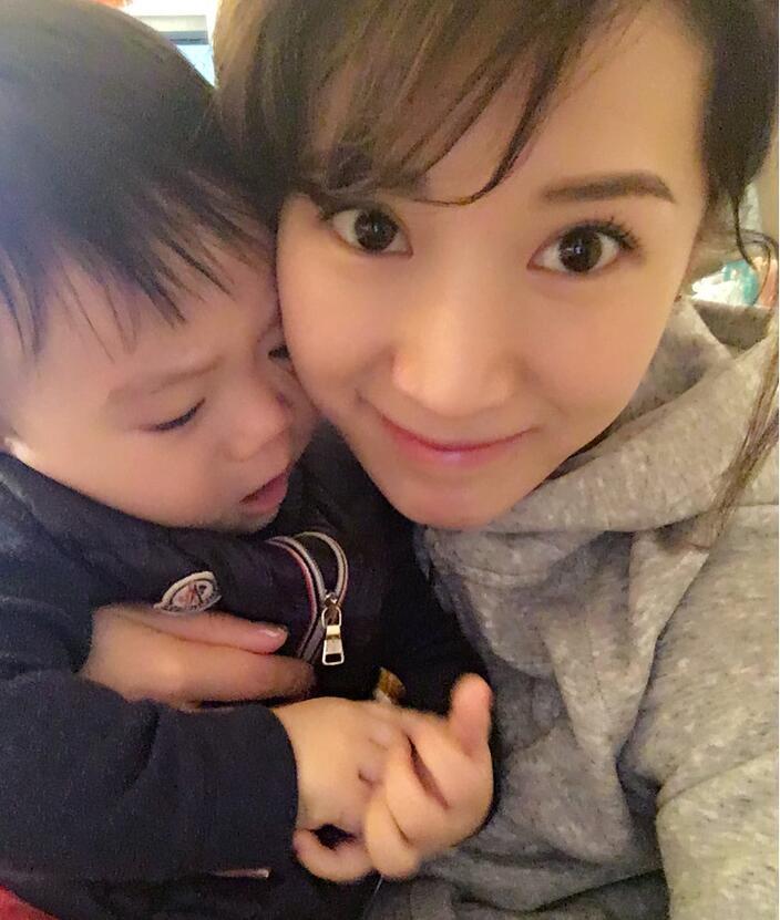 照片中李念狂吻兒子，小寶貝自顧自地玩著。