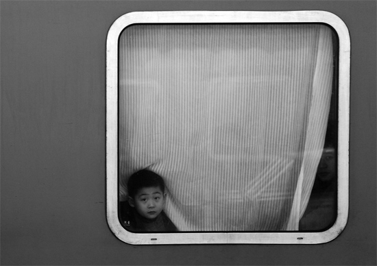 一個(gè)孩子把頭伸向窗外，他想再看送別的親人一眼