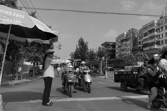 昨日，開(kāi)封市區(qū)一名協(xié)管員在指揮群眾過(guò)馬路