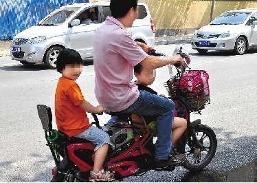 周先生騎著一輛低矮的電動(dòng)車帶著一對兒女，很不安全。
