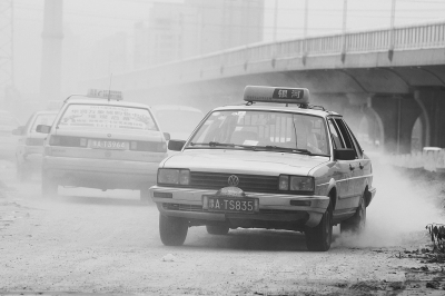 施工的道路上，車輛通過塵土飛揚(yáng)。