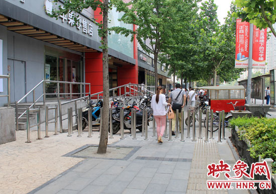 圖中道路左側的無障礙通道被鋼管隔離,右側的盲道也被侵占。