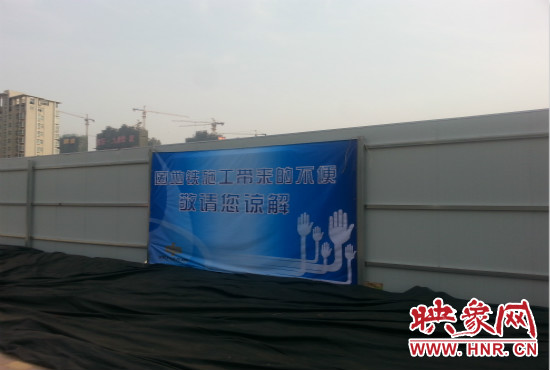 道路南側圍起了白色的圍擋，墻上標示著“因地鐵施工帶來的不便敬請您諒解”的提示牌。