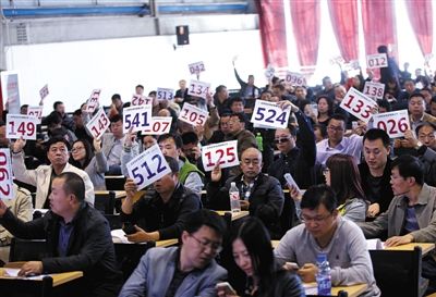 競(jìng)拍者正在練習(xí)舉牌動(dòng)作，以便拍賣時(shí)讓工作人員看清號(hào)牌。