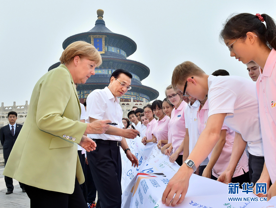 李克強(qiáng)同默克爾在紀(jì)念橫幅上簽名。