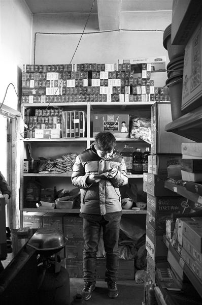 1月21日，周瑋在自家的超市里玩計(jì)算器。