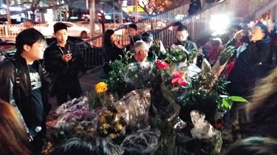 昨晚7時許，三里屯太古里西邊附近一過街天橋旁邊，聞訊而至的網(wǎng)友圍住了賣花老人，爭相買花。 網(wǎng)友“行者橙子”供圖